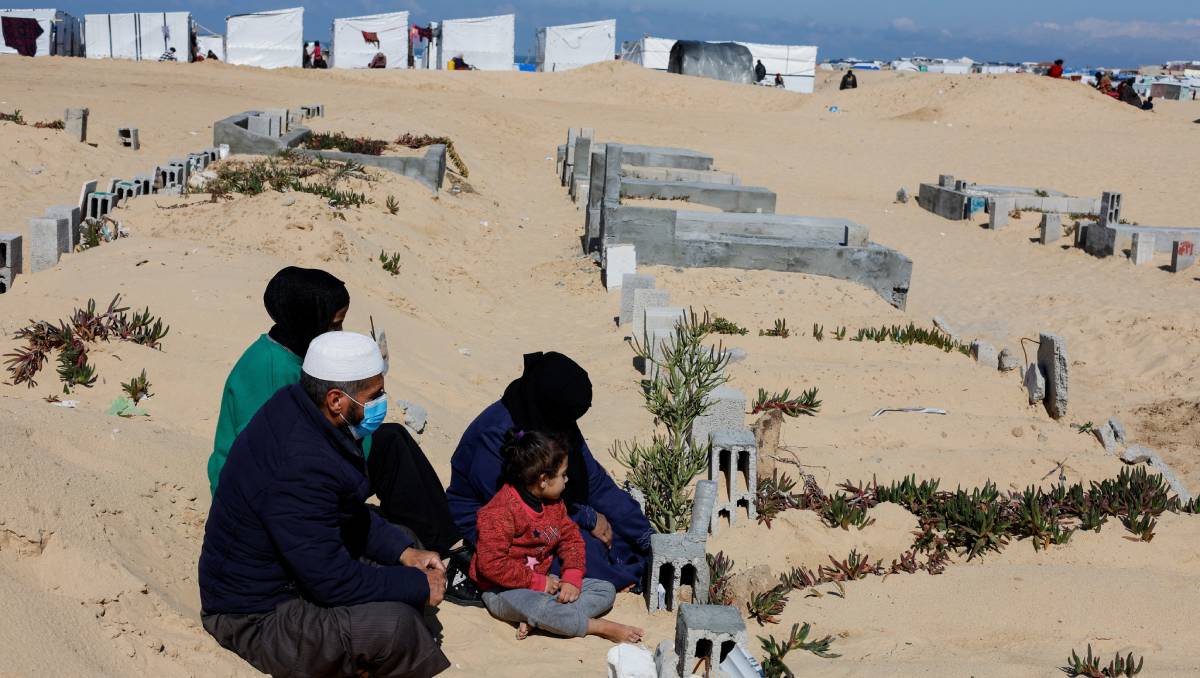 La historia de Mahmoud Amer y su familia refleja la cruda realidad que enfrentan muchos palestinos en la Franja de Gaza, donde la violencia y los desplazamientos son una constante. Después de haber sido desplazados repetidamente debido a las ofensivas militares israelíes, Amer y su familia han encontrado un lugar inesperado para refugiarse: cerca de un cementerio en Ráfah. Esta zona, con sus tumbas antiguas y recientes, se ha convertido en un oasis de relativa seguridad en medio del caos. Para Amer y su familia, este lugar representa una pausa momentánea en la constante amenaza de bombardeos y violencia. Sin embargo, la situación es desgarradora. La falta de alimentos y agua es una realidad diaria para ellos, agravada por el miedo constante a los ataques. Los niños juegan entre las tumbas, un recordatorio sombrío de la tragedia que rodea sus vidas. Para Amer, la guerra ha dejado una marca indeleble, una sensación de muerte omnipresente que lo persigue constantemente. Detrás de esta historia se encuentra el contexto de décadas de conflicto entre Israel y Palestina, con la Franja de Gaza como uno de los epicentros de esta lucha. Los ataques, desencadenados tanto por milicias palestinas como por la respuesta militar israelí, han dejado miles de muertos y han sumido a la población en un estado de desesperación y sufrimiento inimaginable. La historia de Amer y su familia es solo una entre las muchas tragedias que se viven a diario en Gaza, donde la vida cotidiana está marcada por la violencia, la pérdida y la lucha por la supervivencia. Mientras tanto, la búsqueda de una solución duradera al conflicto sigue siendo esquiva, dejando a las familias como la de Amer atrapadas en un ciclo interminable de sufrimiento y desesperanza.